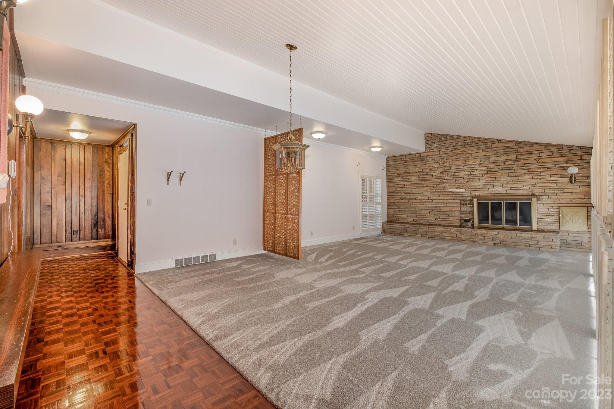 Front door entrance to living room/dining room area separate by a work of art and grounded by a stone wall and fireplace. - 2756 Peachtree Road, Statesville