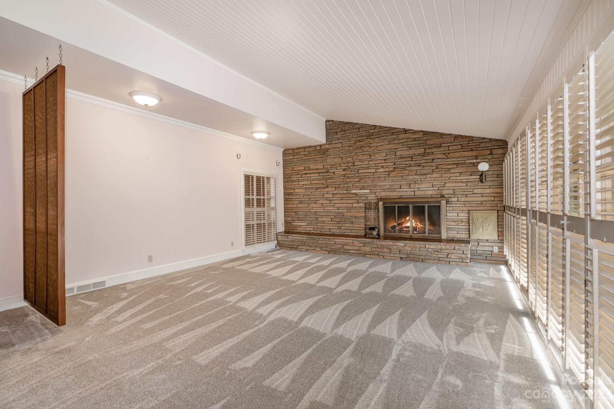 Beautiful room with stone fireplace and a wall of windows for natural light. - 2756 Peachtree Road, Statesville