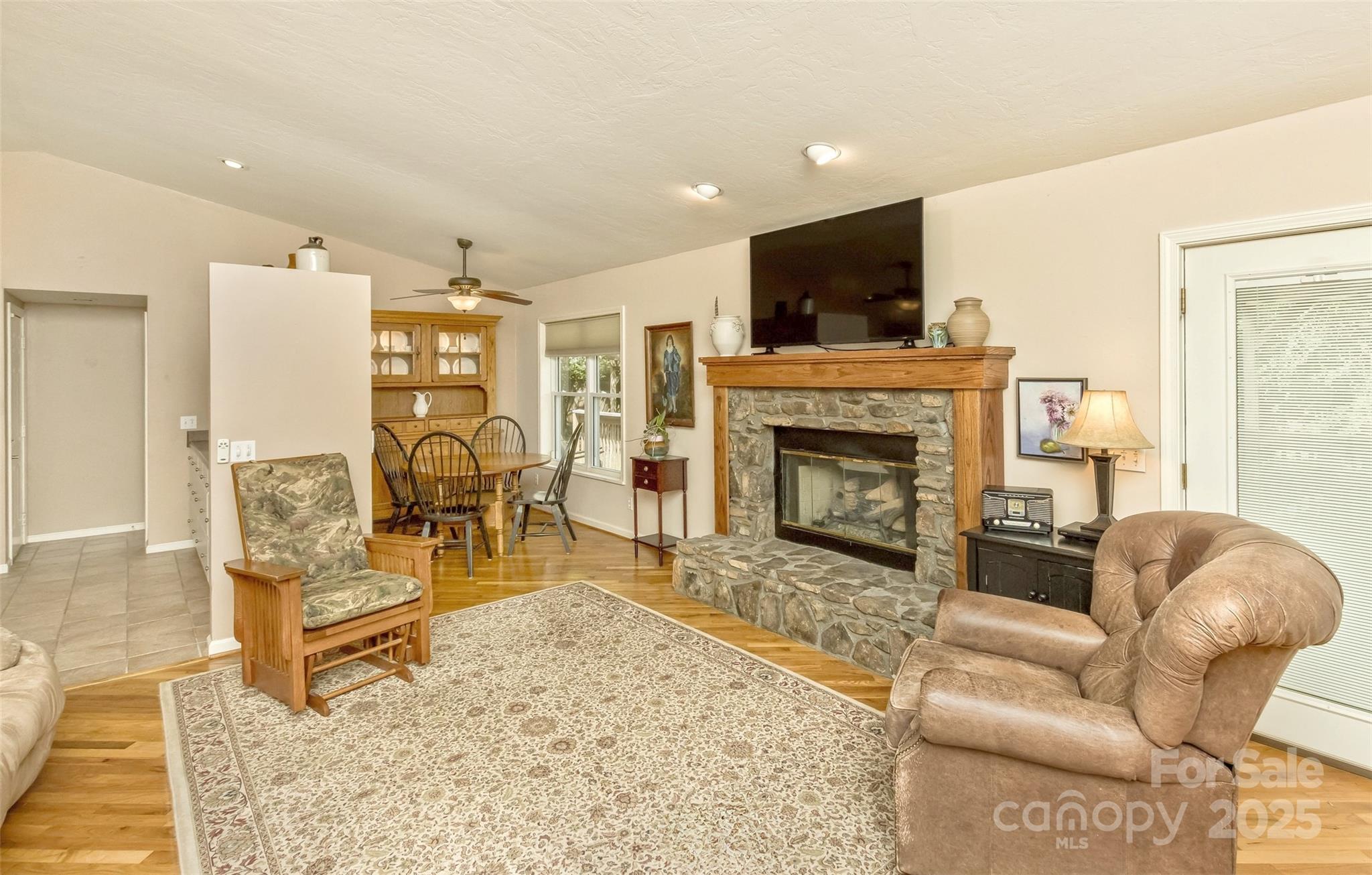 The great room is cozy with a beautiful stone fireplace, oak mantel and natural gas logs. The mantel is designed with chases in the columns to hide wiring needs. - 15 Beaverdam Knoll Road, Asheville