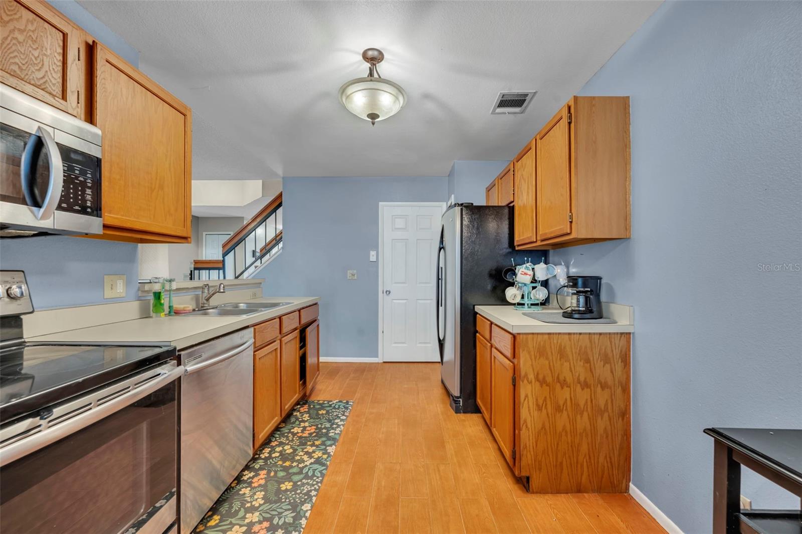 The kitchen also includes the laundry room hidden behind the white door and smartly uses the often unused space under the stairs leading to the double primary bedrooms - 2810 CORNERSTONE CT, APOPKA