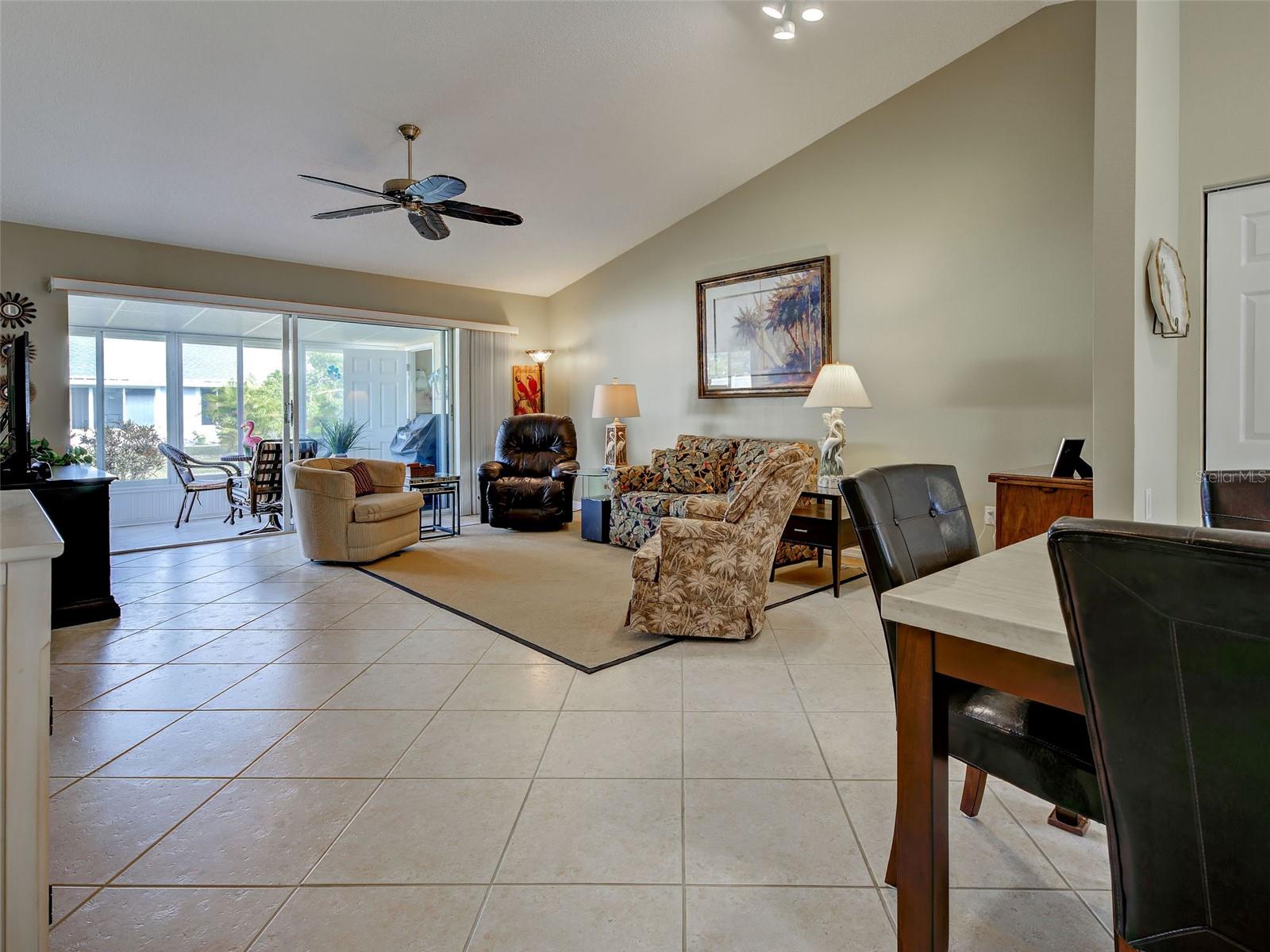 living room with high cathedral ceiling, tile flooring, sliding glass doors to lanai. Open floor plan - 6527 HAMLET DR #26B, ENGLEWOOD