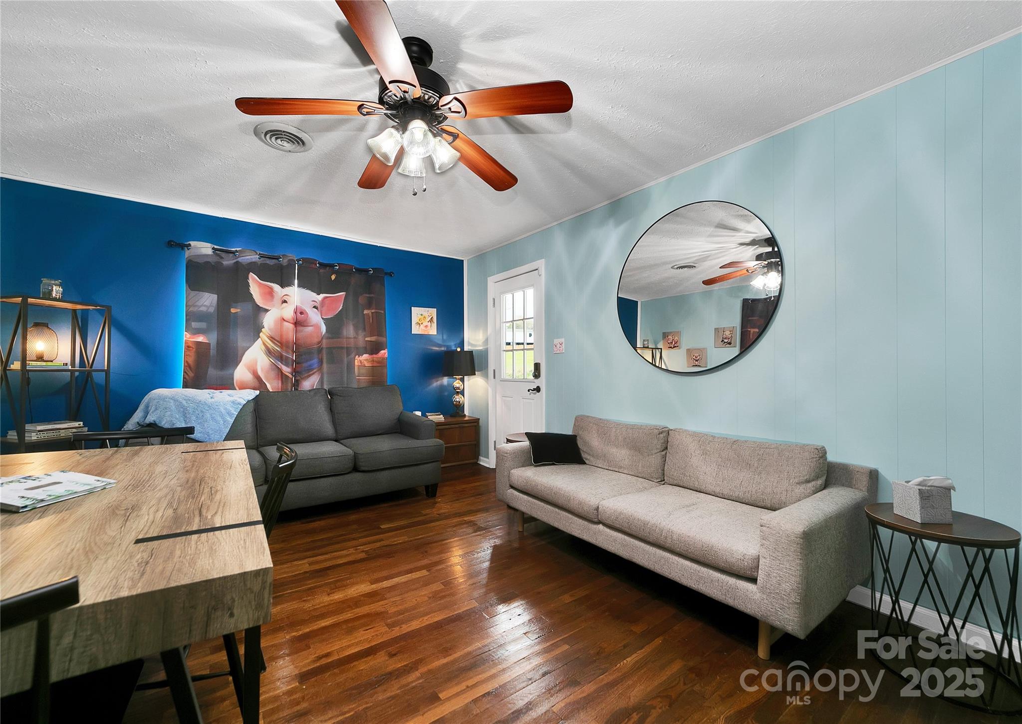 Living Room, decorated with piggies, looking back toward the front door out to the front porch. The middle bedroom is alive with bunny rabbits in every corner! Light and bright with beautiful oak hardwood floors. - 626 Fairview Loop, Hot Springs
