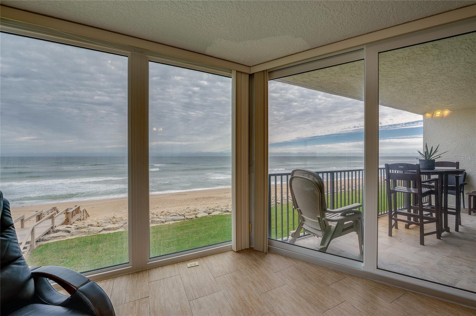 Expansive glass doors open directly to the covered balcony, creating seamless indoor-outdoor flow and capturing stunning views of the sand and surf. - 6727 TURTLEMOUND RD #315, NEW SMYRNA BEACH