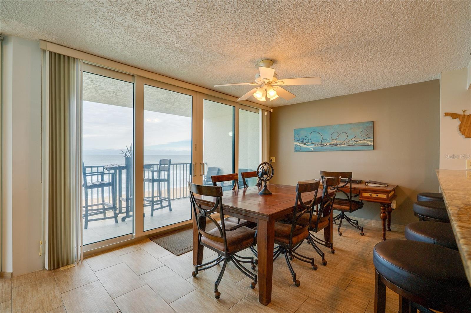 A spacious dining area with sliding glass doors offers direct access to the balcony and sweeping coastal views perfect for gathering with friends or enjoying sunset dinners. - 6727 TURTLEMOUND RD #315, NEW SMYRNA BEACH
