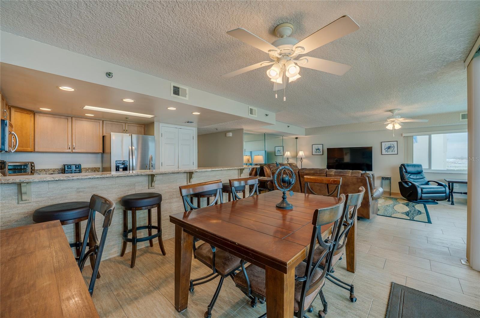 A central dining area connects to the kitchen and living space, all under ceiling fans and surrounded by windows—ideal for casual meals and gatherings. - 6727 TURTLEMOUND RD #315, NEW SMYRNA BEACH