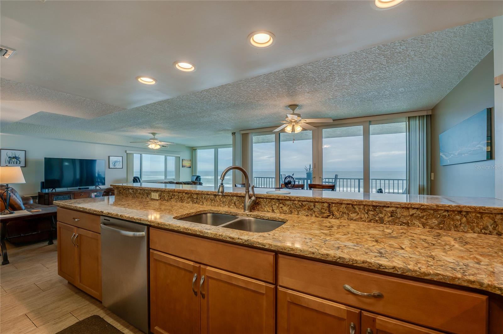 Enjoy breathtaking ocean views directly from the kitchen sink, with an open sightline through the dining and living areas to the balcony beyond. - 6727 TURTLEMOUND RD #315, NEW SMYRNA BEACH