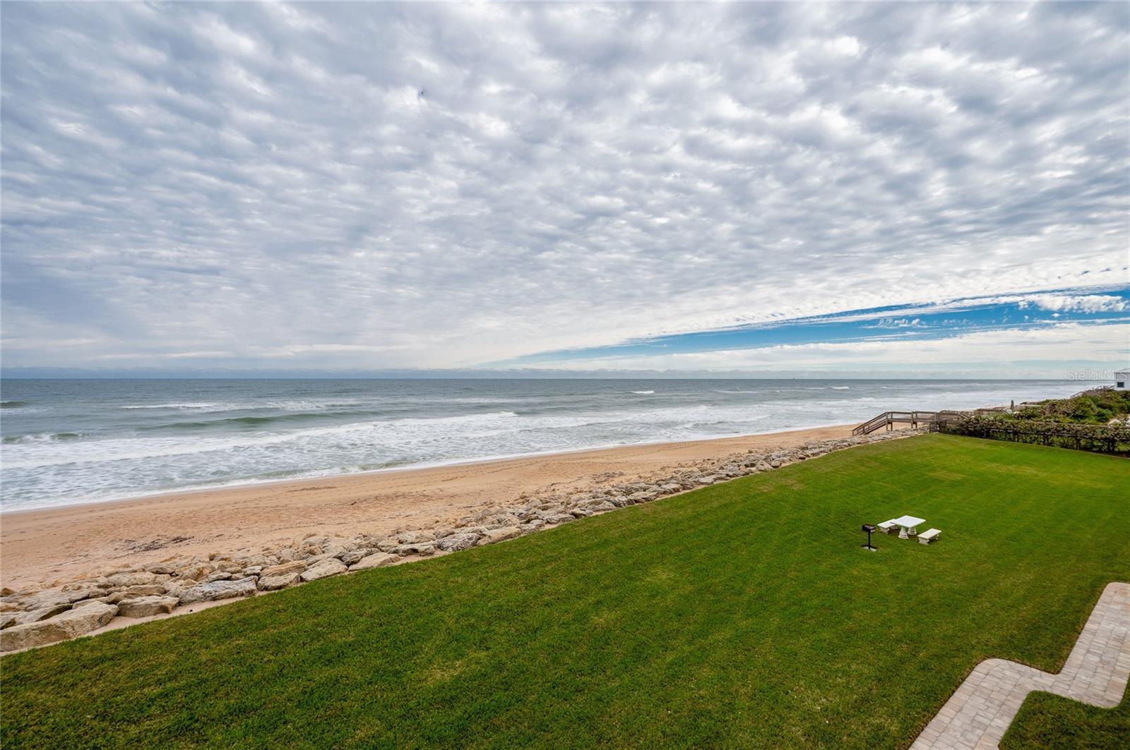 A lush green lawn frames wide ocean views and provides open space between the residence and the shoreline, ideal for outdoor lounging or play. - 6727 TURTLEMOUND RD #315, NEW SMYRNA BEACH