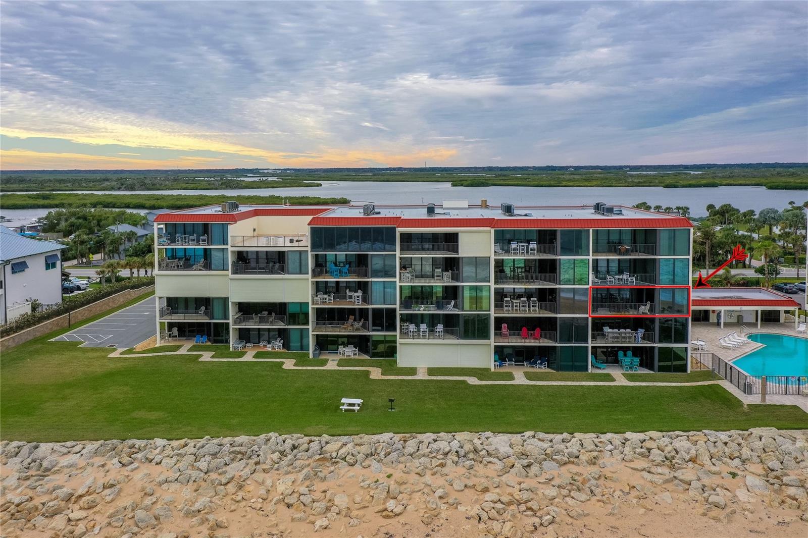 A close-up of the east-facing elevation reveals private balconies, glass-enclosed sunrooms, and the building’s direct access to the pool and beach areas. - 6727 TURTLEMOUND RD #315, NEW SMYRNA BEACH