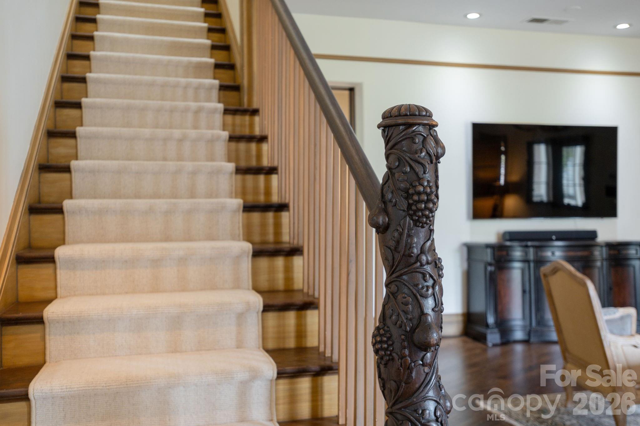 The grand staircase, anchored by an intricately hand-carved banister, showcases the home's exceptional craftsmanship and design. - 8 Fairway Place, Asheville
