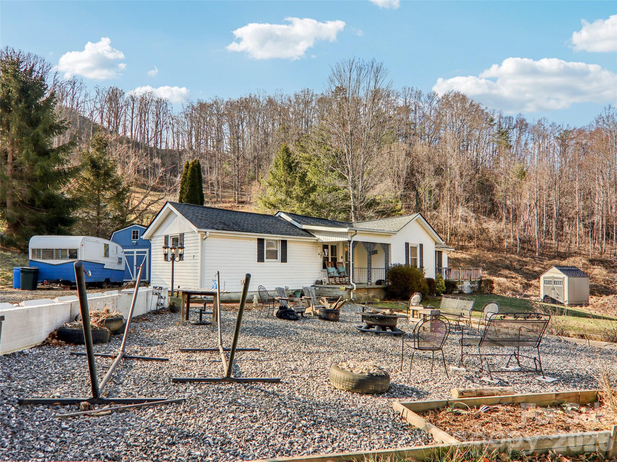 Gravel patio and outdoor seating area located in the front yard, offering a flexible space for relaxing or entertaining with views of the surrounding natural landscape and wooded hillside backdrop - 7 Landon Mountain Lane, Weaverville