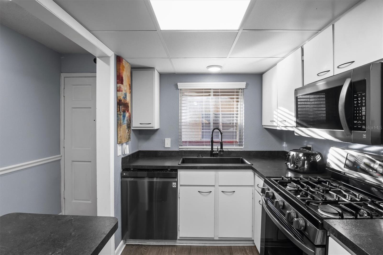The kitchen has a gas stove and stainless steel appliances - 400 EL CAMINO DR #210, WINTER HAVEN