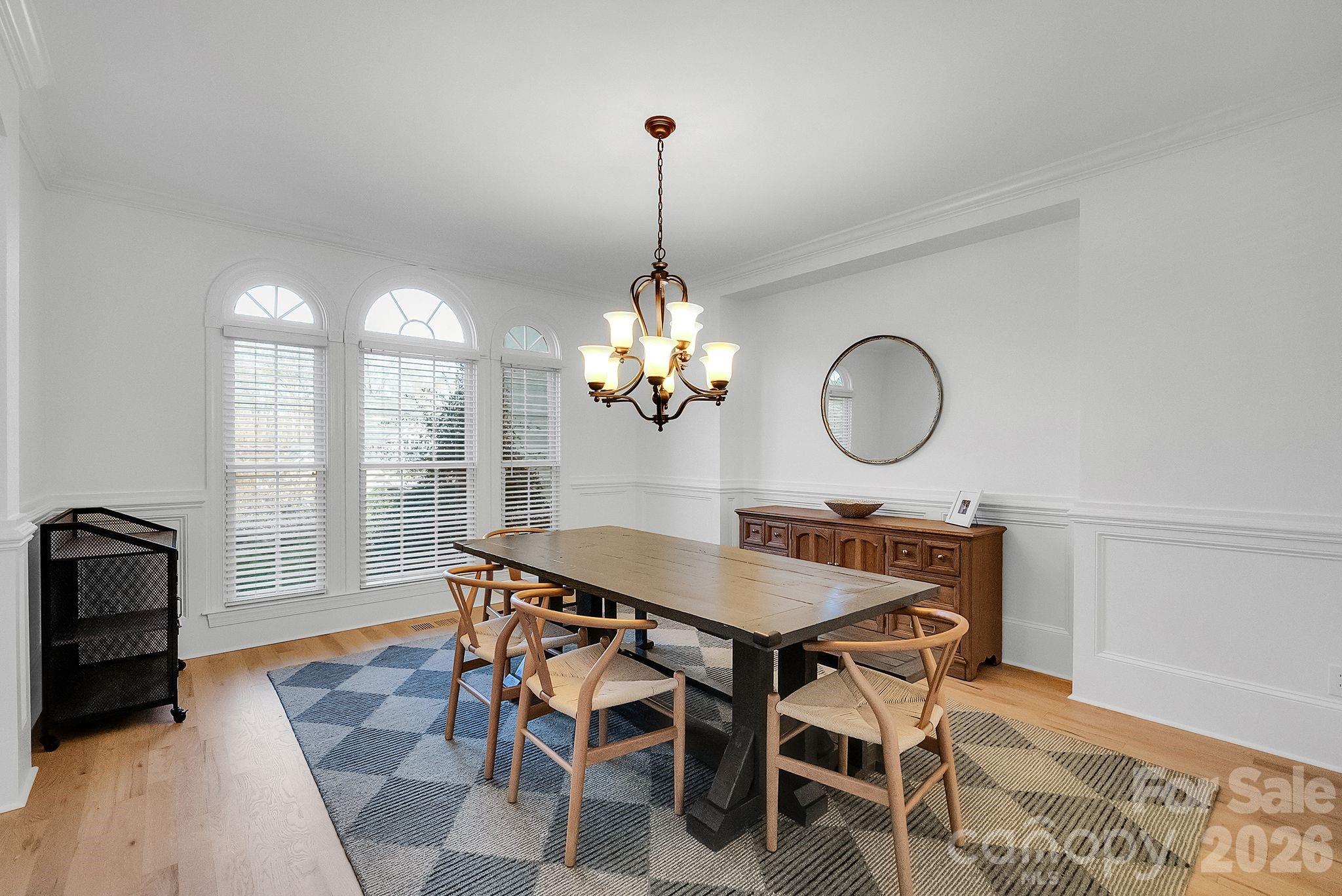Formal dining room highlighted by arched windows, decorative millwork, and a statement chandelier. The space offers an inviting setting for gatherings and entertaining - 7778 Burning Ridge Drive, Stanley