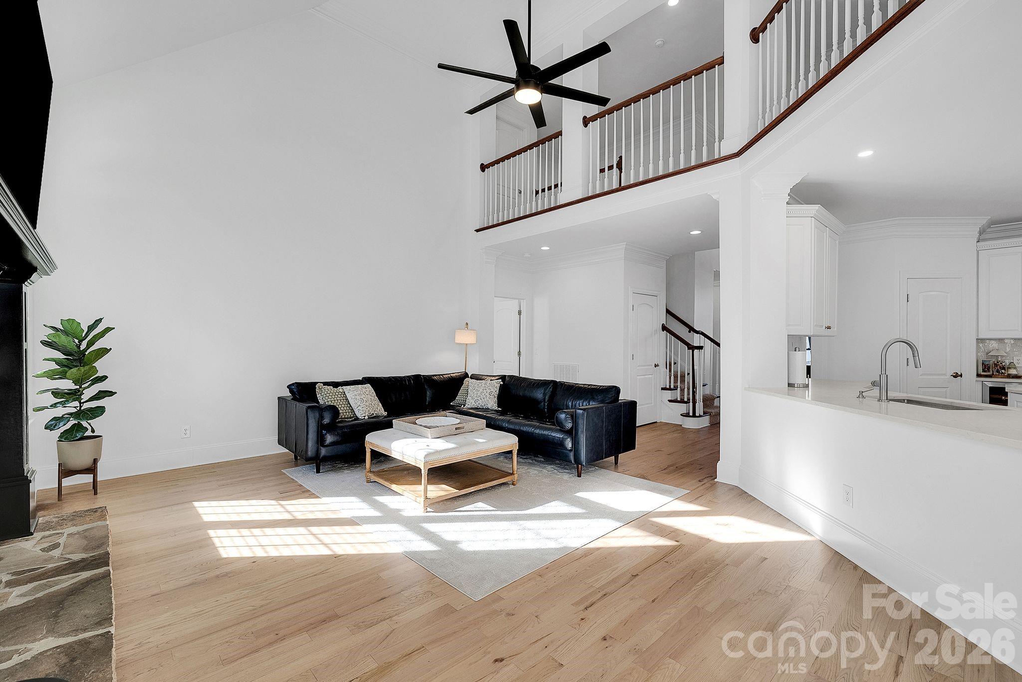 Dramatic living room with soaring ceilings, fireplace focal point, and expansive windows. The open design creates a bright and airy atmosphere. - 7778 Burning Ridge Drive, Stanley