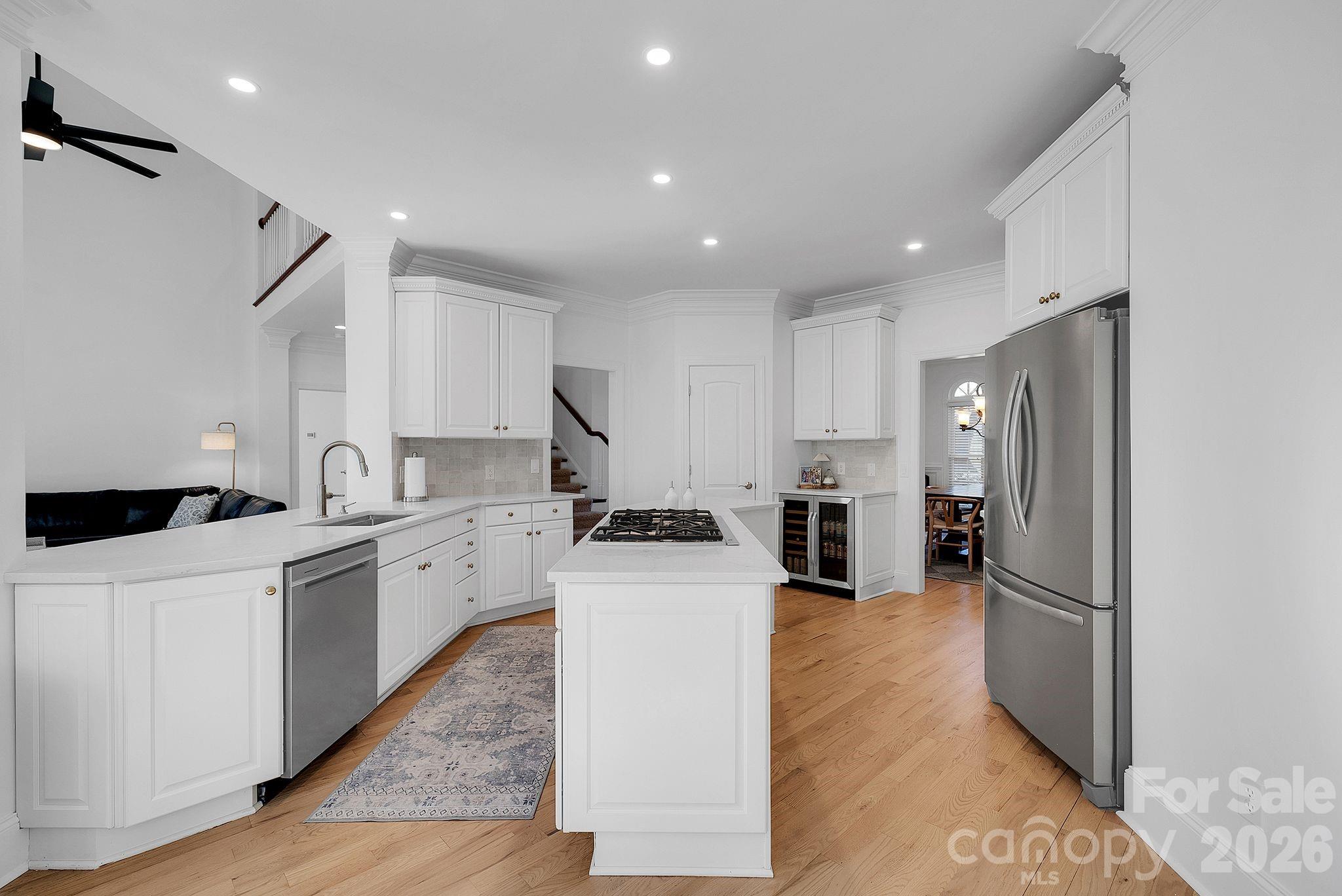 Bright kitchen designed with white cabinetry, quartz countertops, and a large center island with gas cooktop. Open layout connects seamlessly to adjacent living areas. - 7778 Burning Ridge Drive, Stanley