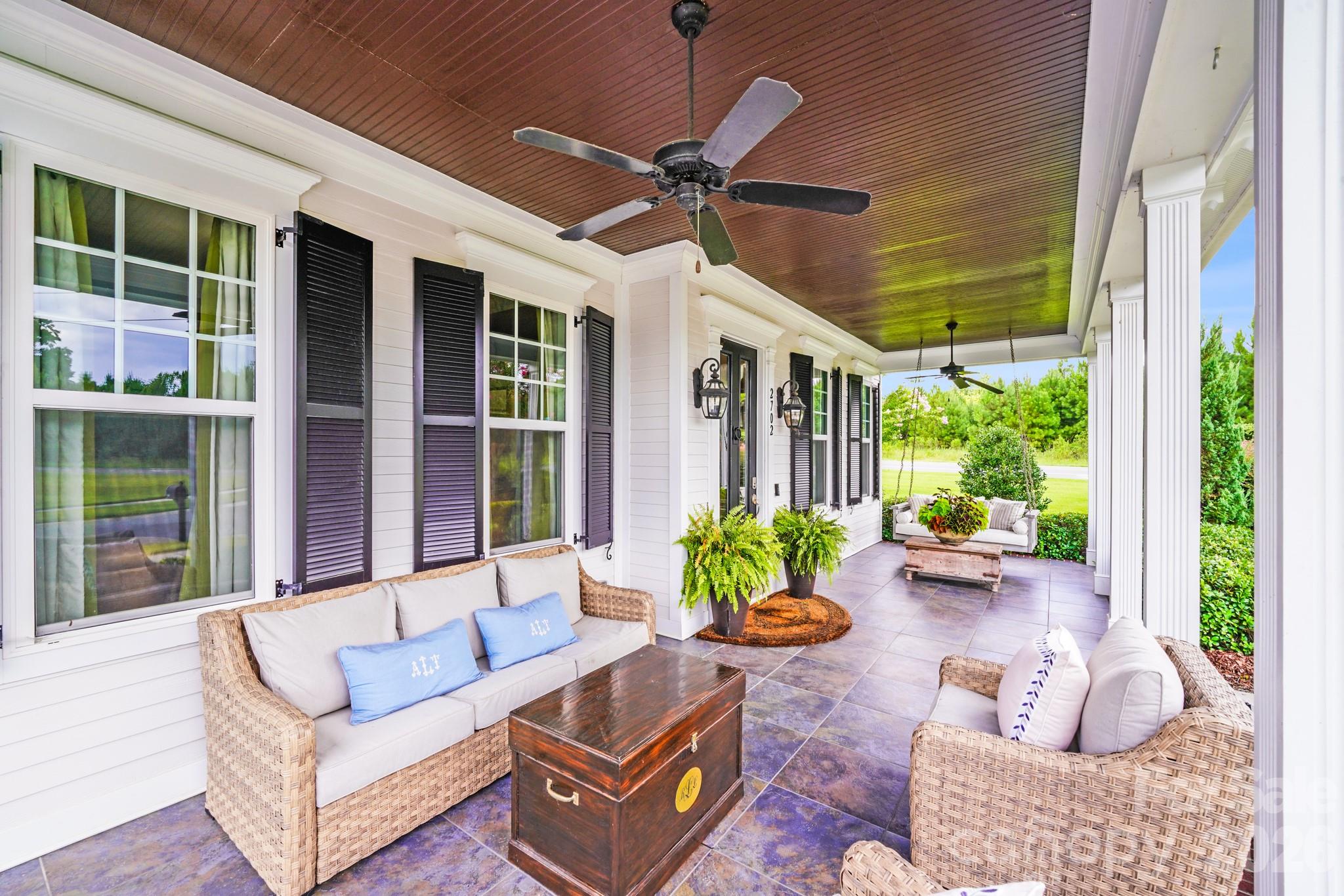 Spacious covered porch features rich wood-paneled ceiling, classic white columns, elegant tile flooring and dual ceiling fans. - 2702 Arsdale Road, Waxhaw