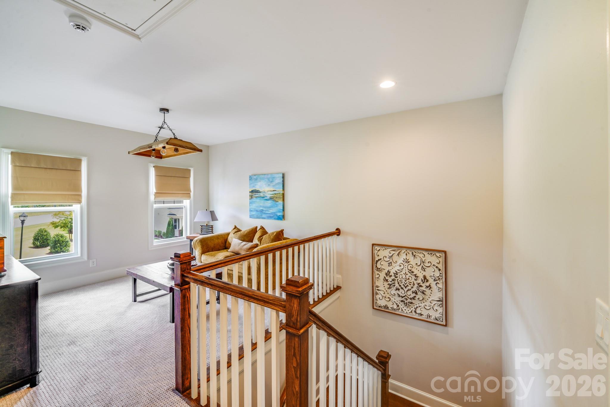 At the top of the stairs, a bright and inviting loft offers the perfect flex space for a cozy reading nook, home office, or media lounge, complete with natural light from two large windows - 2702 Arsdale Road, Waxhaw