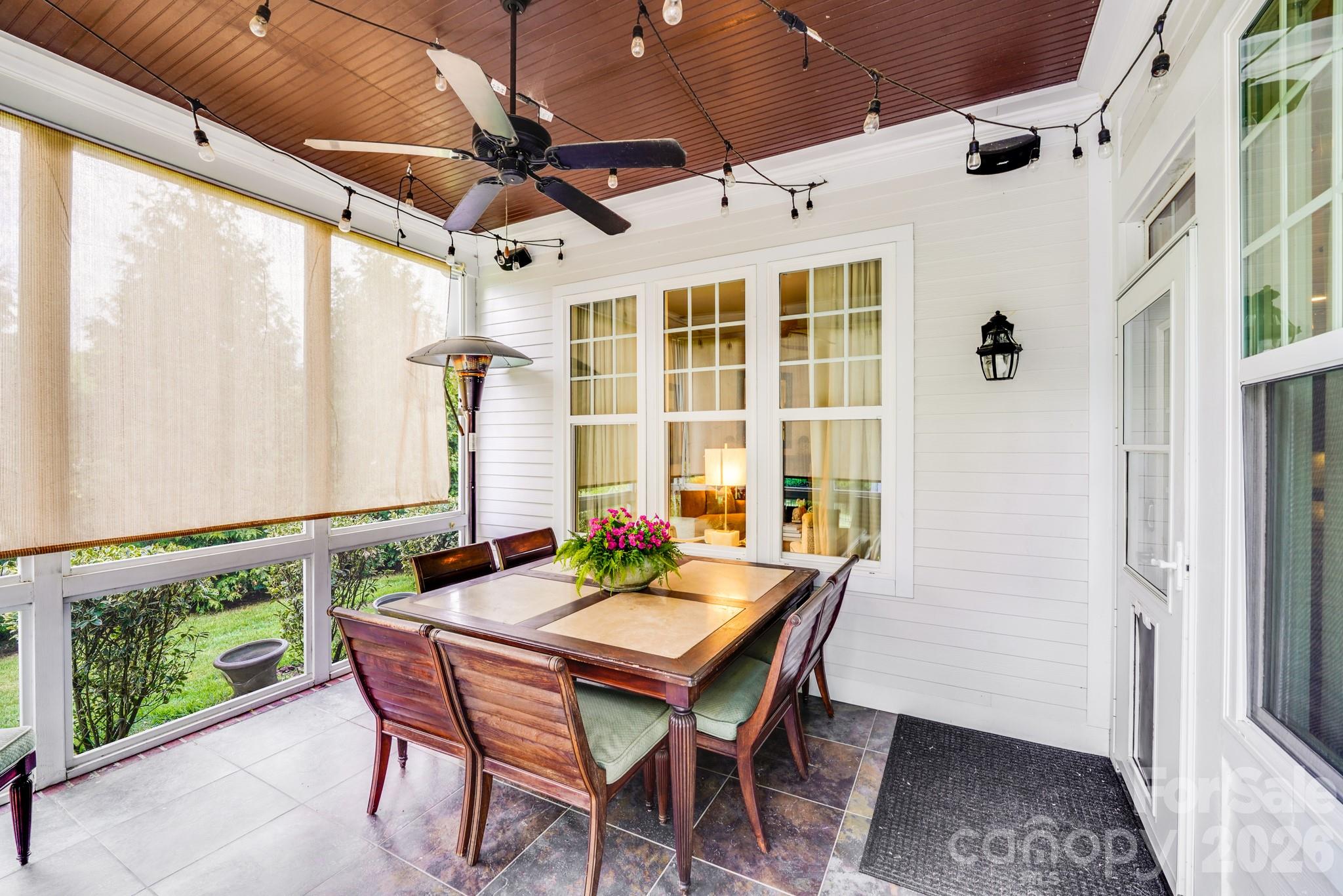 Elegant screened porch, complete with a rich wood-paneled ceiling, string lights, ceiling fan and roll-down shades - 2702 Arsdale Road, Waxhaw
