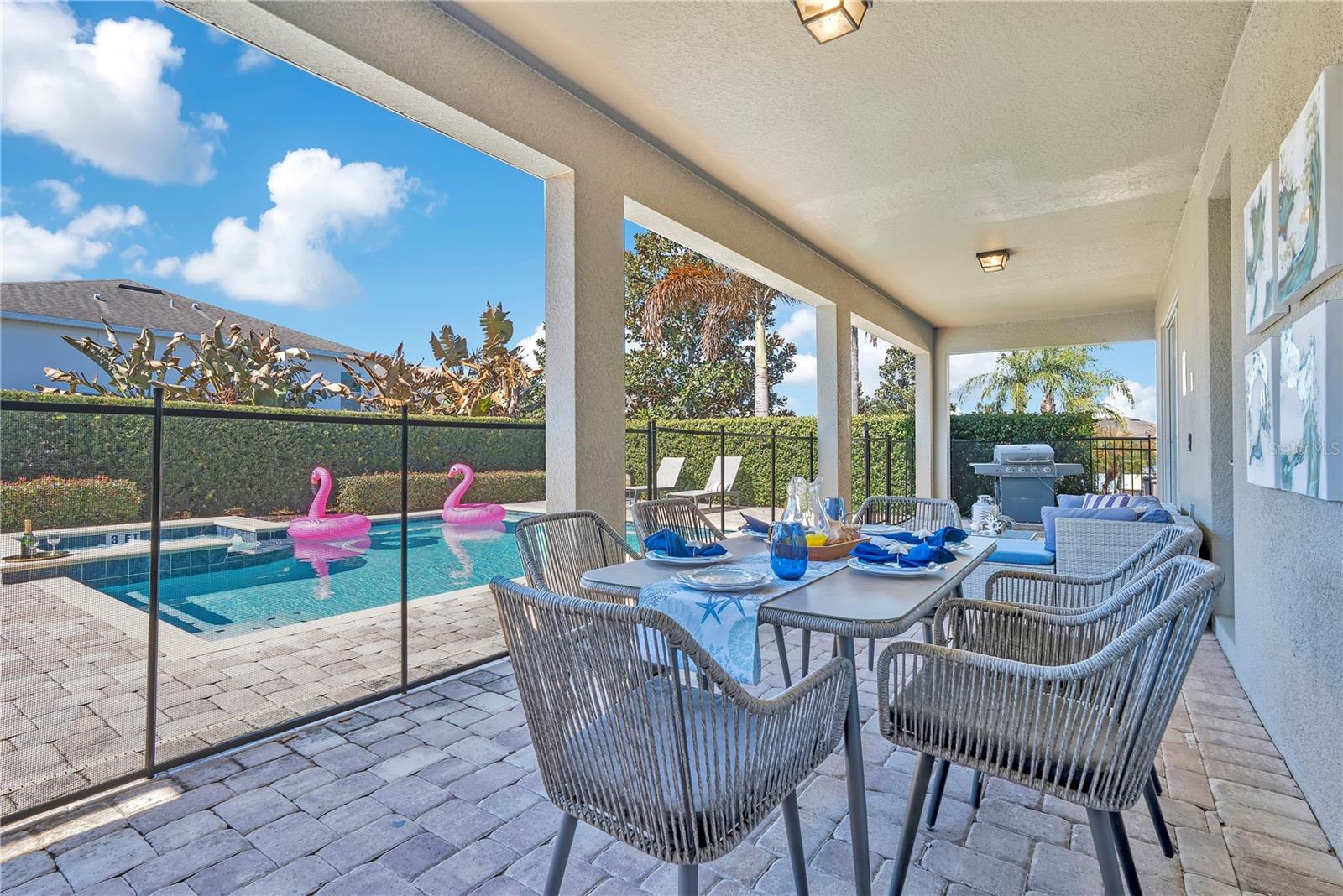 Extended covered lanai with multiple seating areas, perfect for hosting guests in a private retreat setting. - 631 LASSO DR, KISSIMMEE