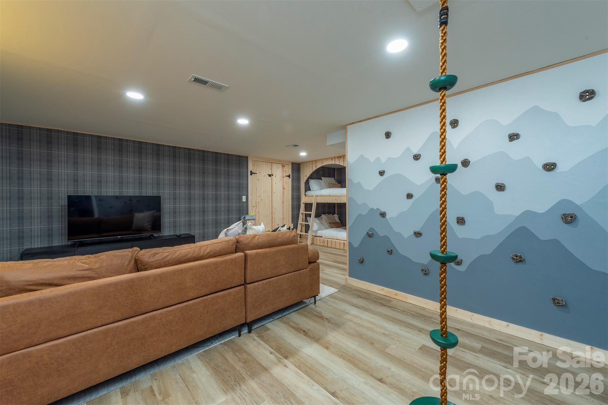 Adventure awaits indoors! The basement family room features a fun climbing wall and rope climb for kids (and adults!) to enjoy endless excitement. - 322 Goldenleaf Road, Mars Hill