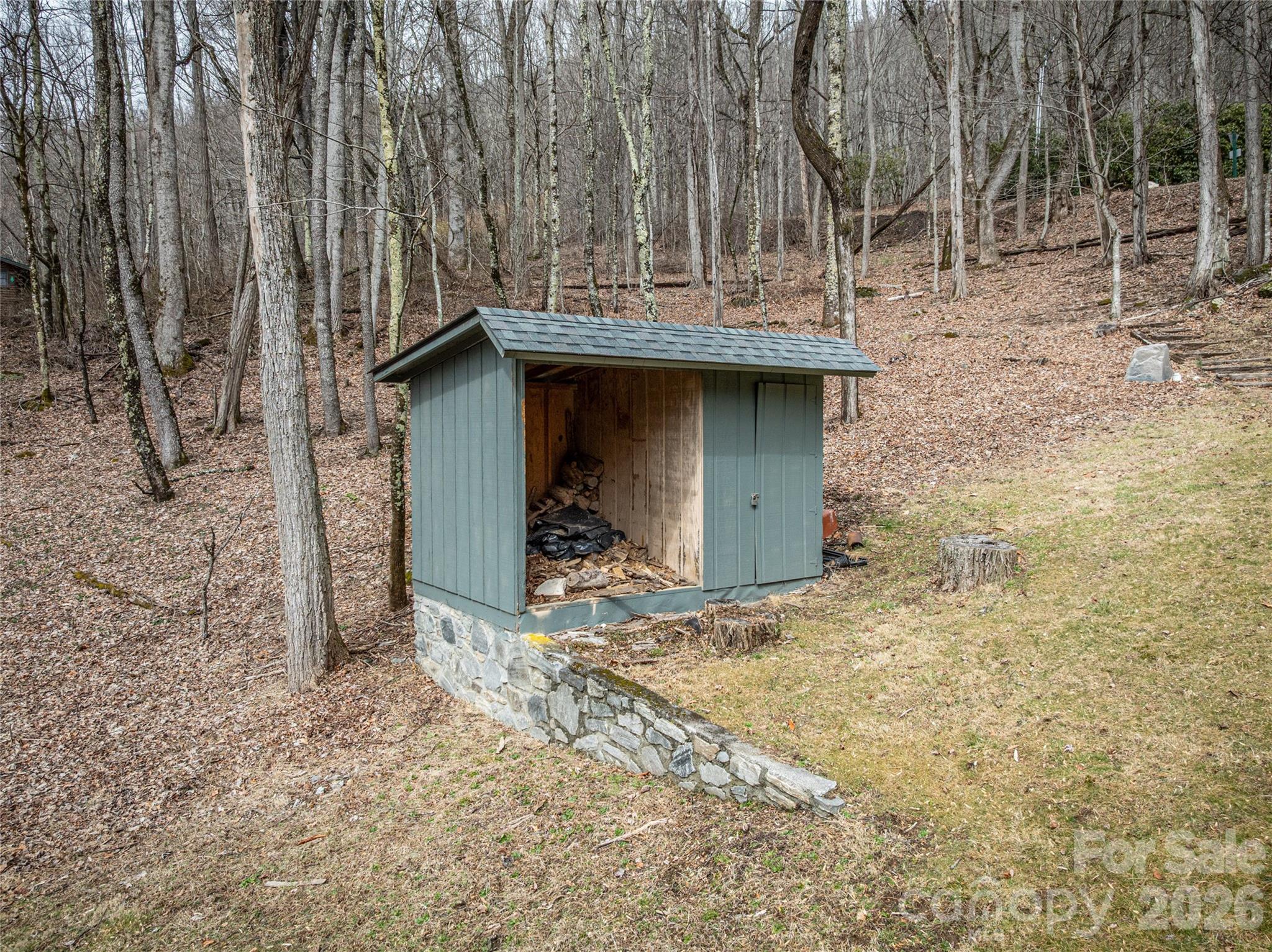 Stone-based accessory structure offering convenient outdoor storage, blending seamlessly with the natural wooded setting. - 453 Friendly Acres Drive, Waynesville
