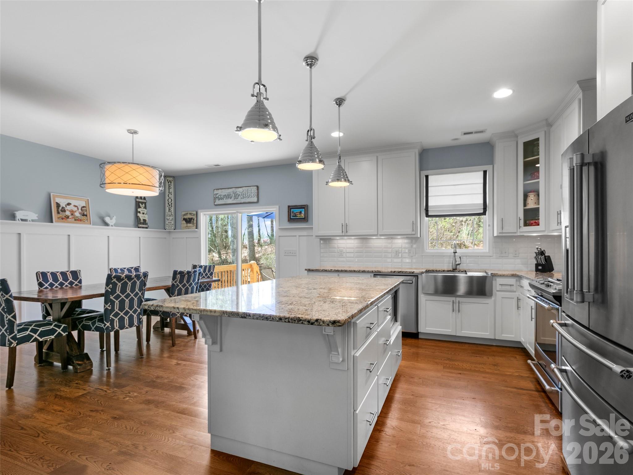 Stylish open kitchen showcasing custom cabinetry, stainless steel appliances, and an oversized island perfect for cooking, dining, and entertaining - 290 Sweetwater Hills Drive, Hendersonville