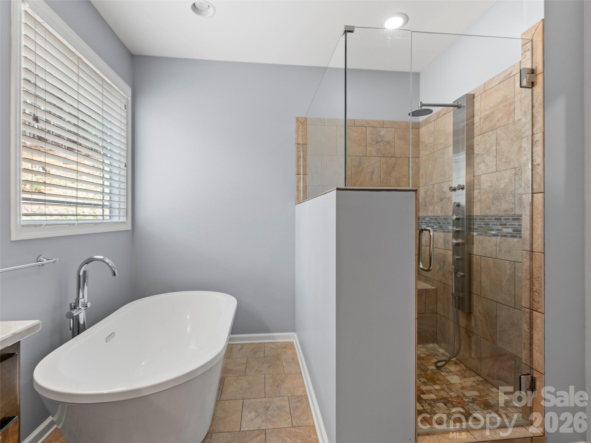 Spa-inspired primary bath featuring a walk-in shower, soaking tub, private water closet, and a custom-designed walk-in closet for elevated everyday living - 290 Sweetwater Hills Drive, Hendersonville