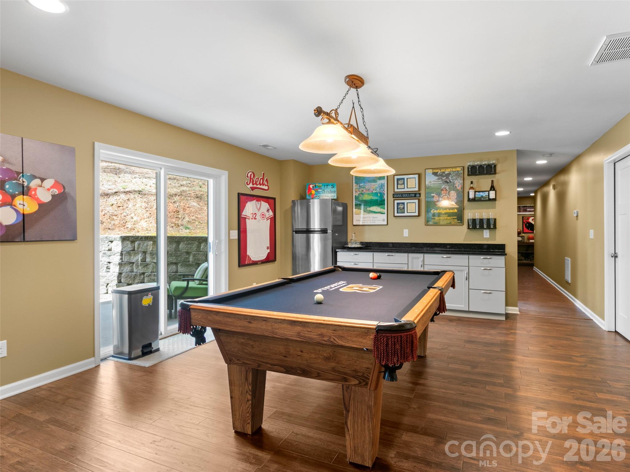 Sophisticated game room with a billiards area, custom cabinetry, granite surface, built-in refrigeration, and a striking chandelier centerpiece - 290 Sweetwater Hills Drive, Hendersonville