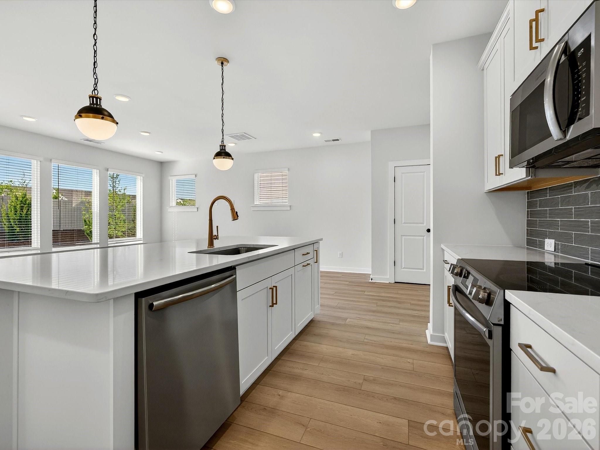 42" white cabinets with soft close doors & drawers. Quartz Countertops, large Island with shiplap. Large corner pantry with solid shelving. Frigidaire gallery appliances. LVP flooring throughout the main floor. - 202 Quartz Hill Way, Waxhaw