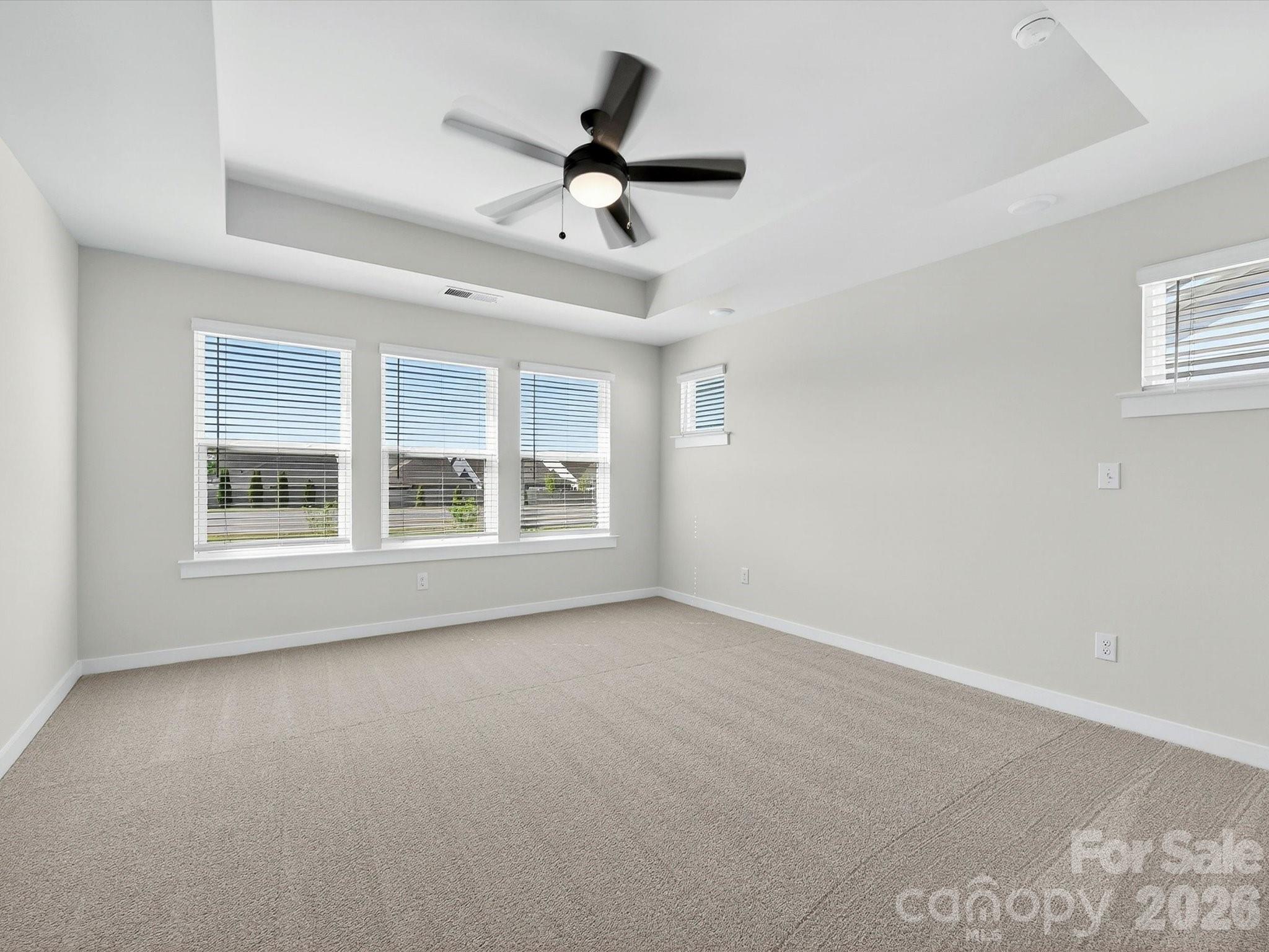 Primary bedroom with tray ceiling is filled with natural light. - 202 Quartz Hill Way, Waxhaw