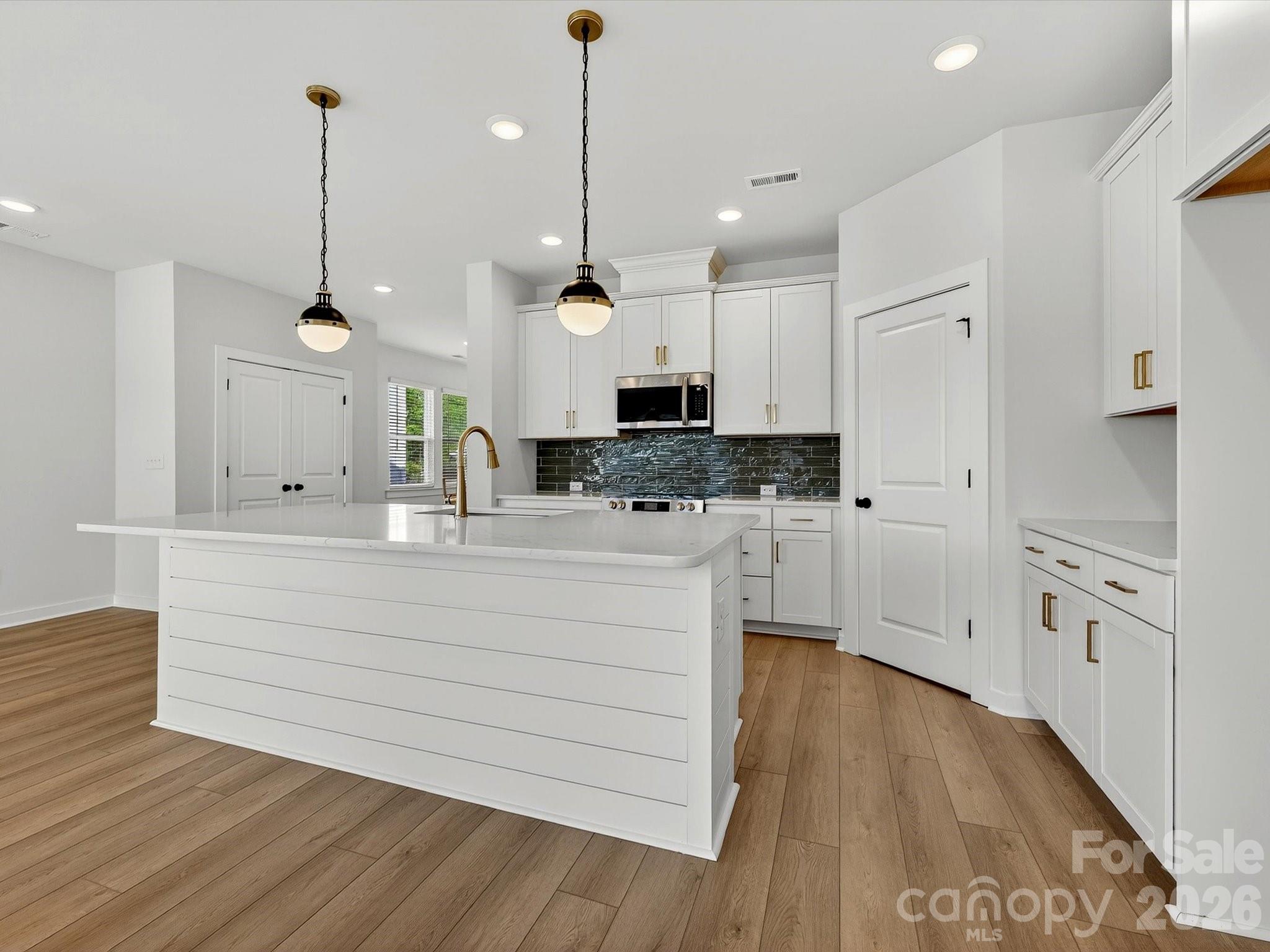 42" white cabinets with soft close doors & drawers. Quartz Countertops, large Island with shiplap. Large corner pantry with solid shelving. Frigidaire gallery appliances. LVP flooring throughout the main floor. - 202 Quartz Hill Way, Waxhaw