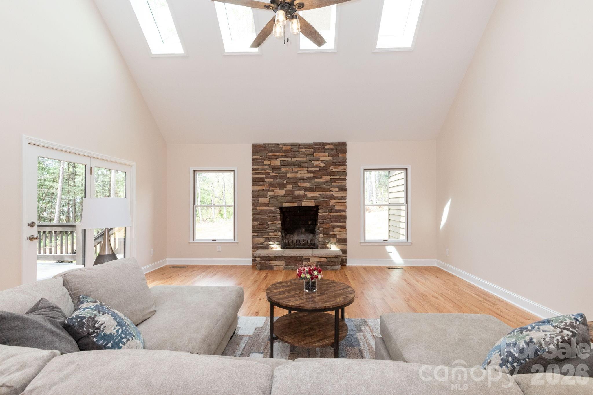 Stunning living room with vaulted ceilings, skylights, and a beautiful stone fireplace as the focal point. - 68 Sigmon Road, Fletcher