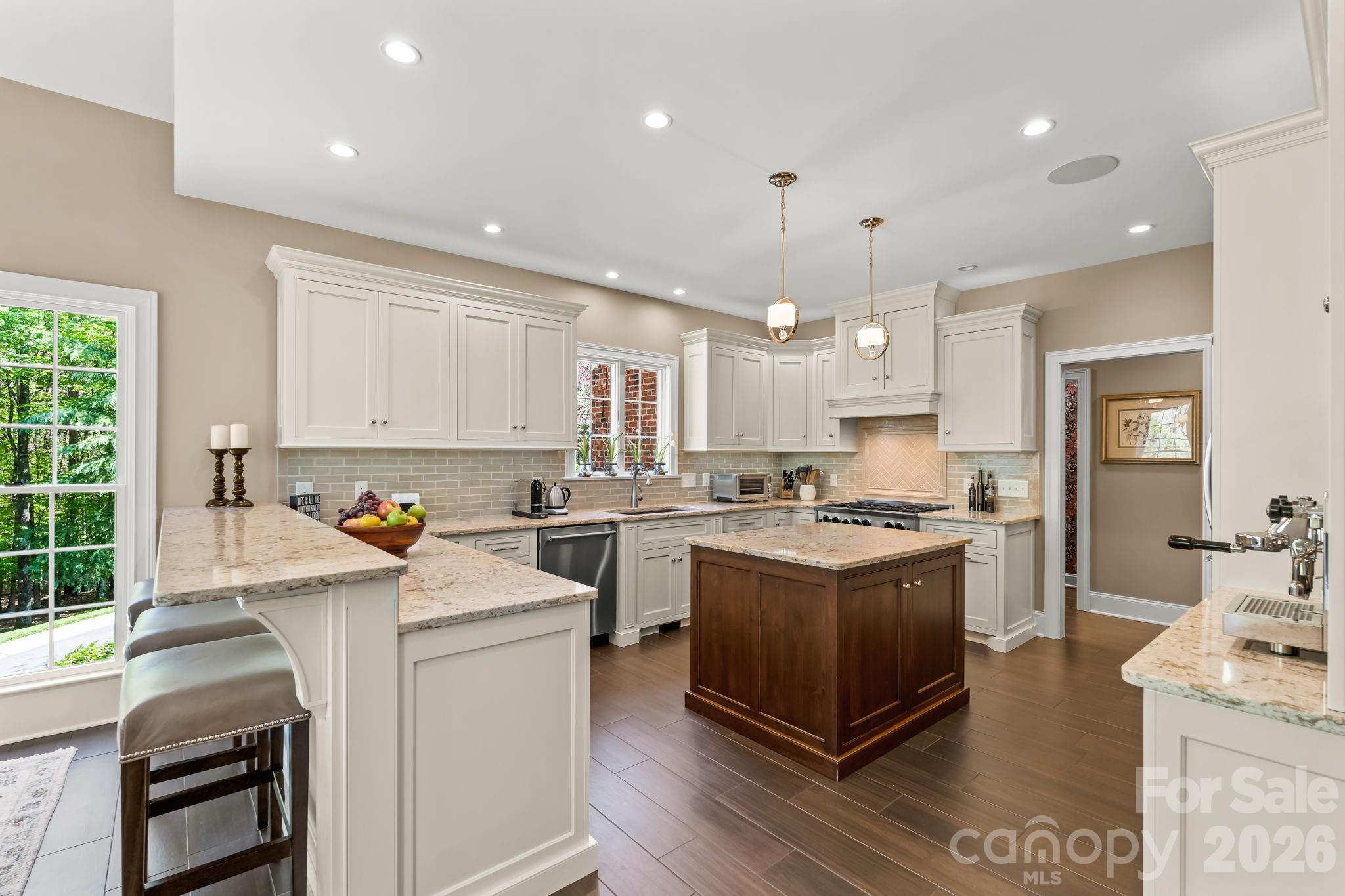 Thoughtfully renovated kitchen with quartz countertops, custom cabinets, bar seating, and pendant lighting - 11555 Double Spring Road, Lewisville