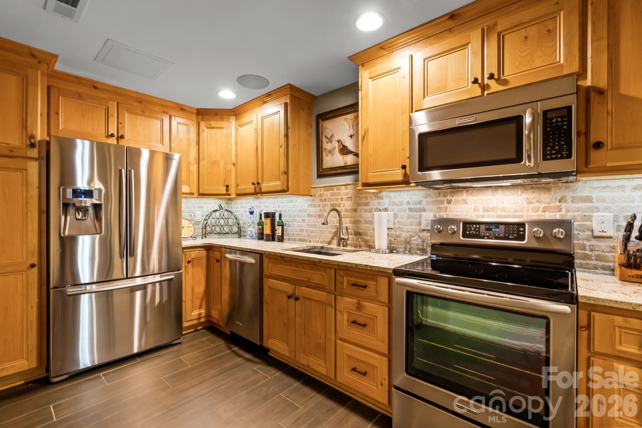 Lower level, fully equipped kitchen with quartz countertops, stainless appliances, tiled backsplash and beautiful cabinetry - 11555 Double Spring Road, Lewisville