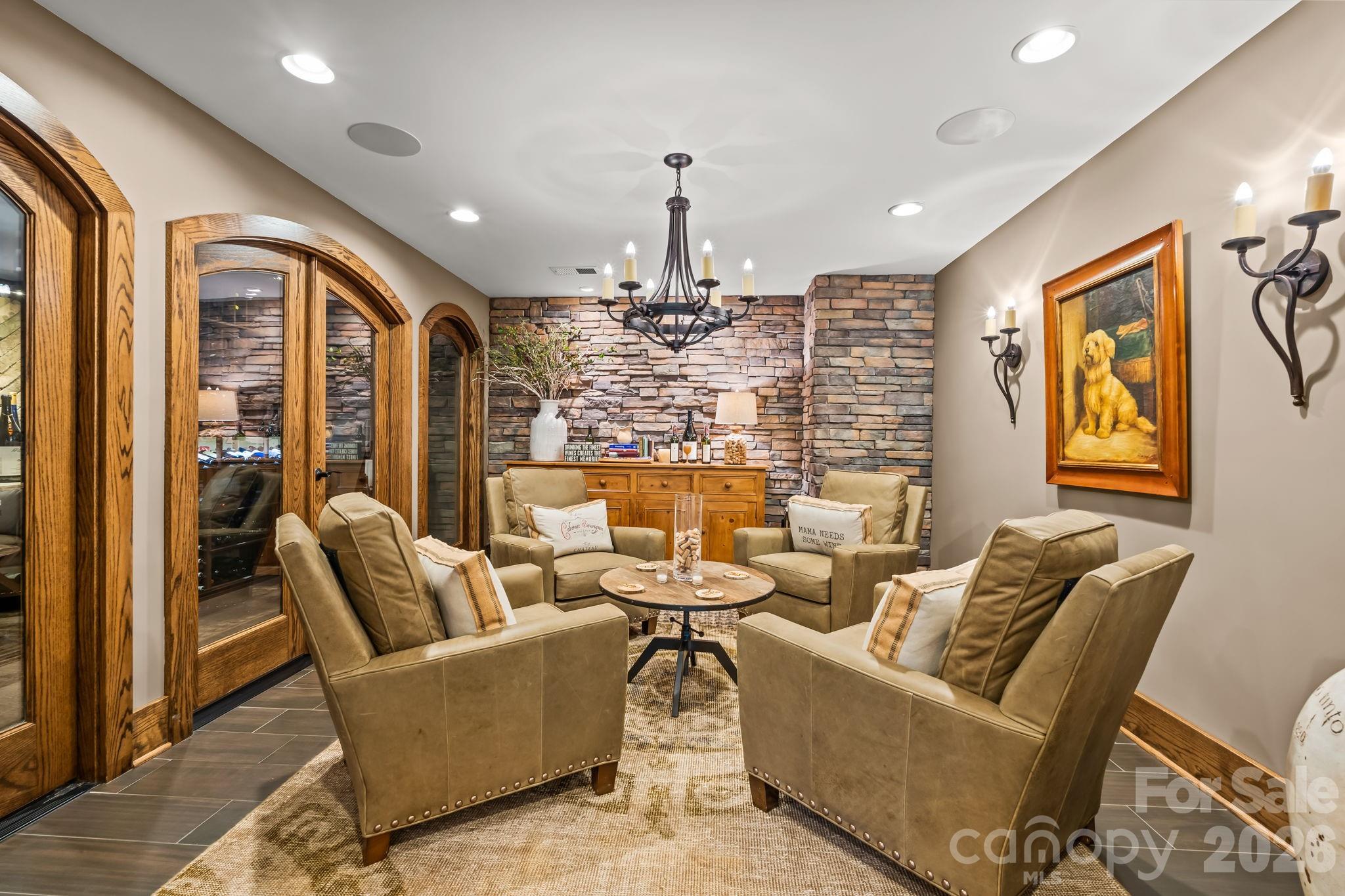 The tasting room with stone clad wall, wood trim, chandelier, and front row seats to the wine cellar. - 11555 Double Spring Road, Lewisville