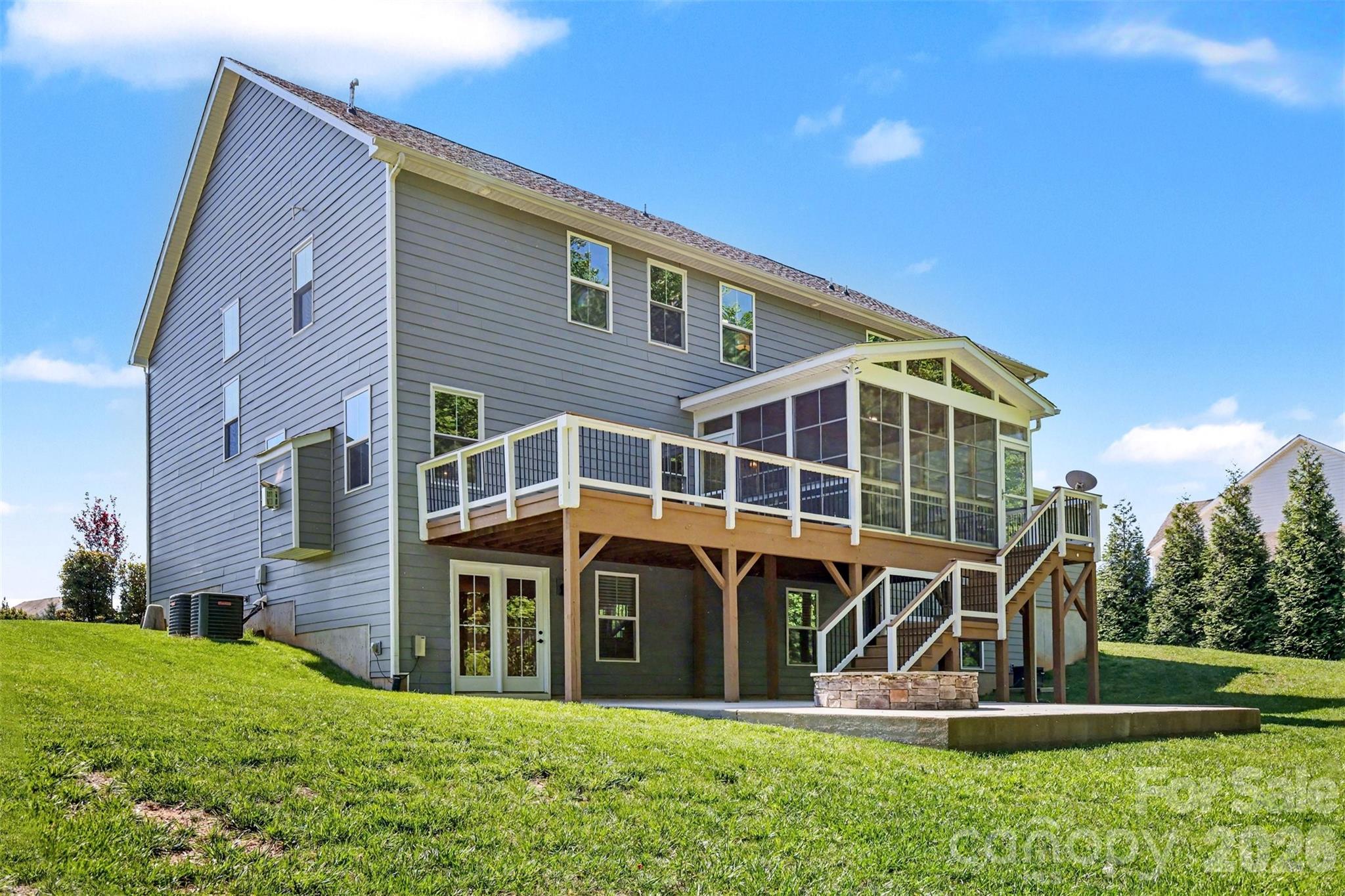 Rear exterior of home featuring enclosed porch, open deck, and lower level patio with fire pit. - 824 Abbeywood Drive, Waxhaw