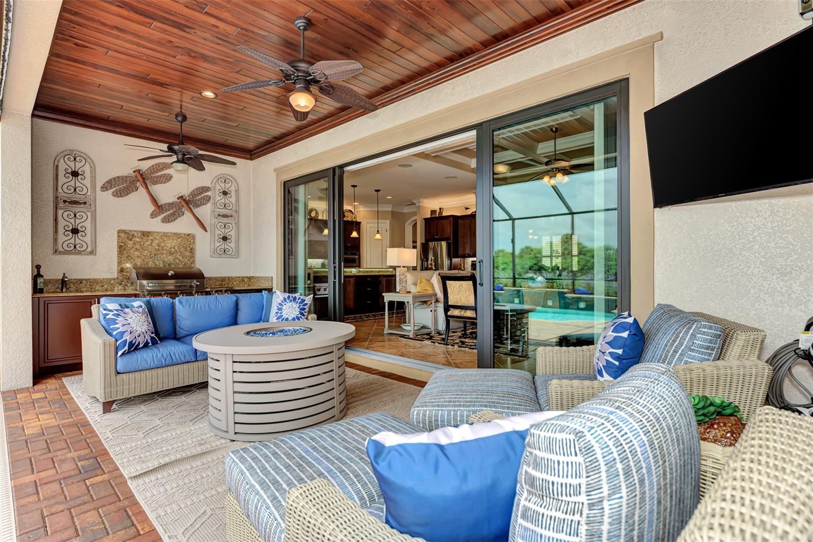 Looking out through French Glass Sliding Doors you will find an outside kitchen meticulously cared for, with wood paneled ceiling, television, sound system, and luxurious pool. - 10965 BULLRUSH DR, VENICE
