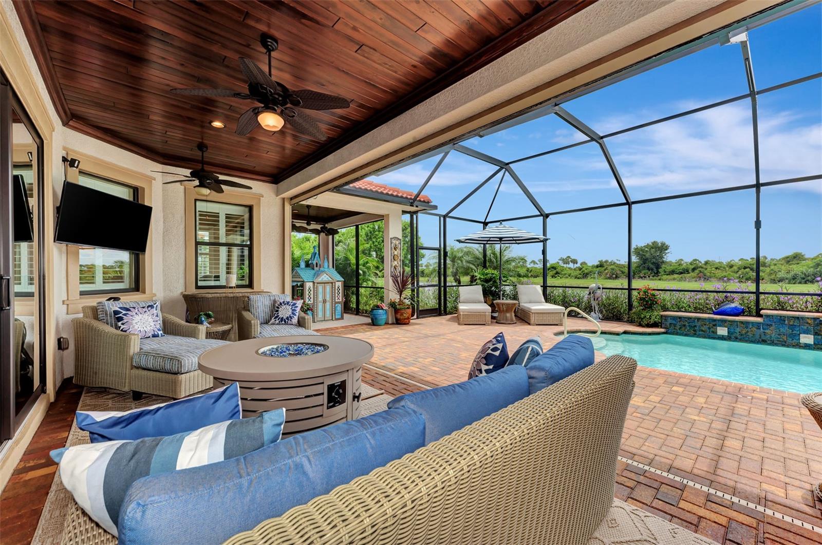 Looking out through French Glass Sliding Doors you will find an outside kitchen meticulously cared for, with wood paneled ceiling, television, sound system, and luxurious pool. - 10965 BULLRUSH DR, VENICE