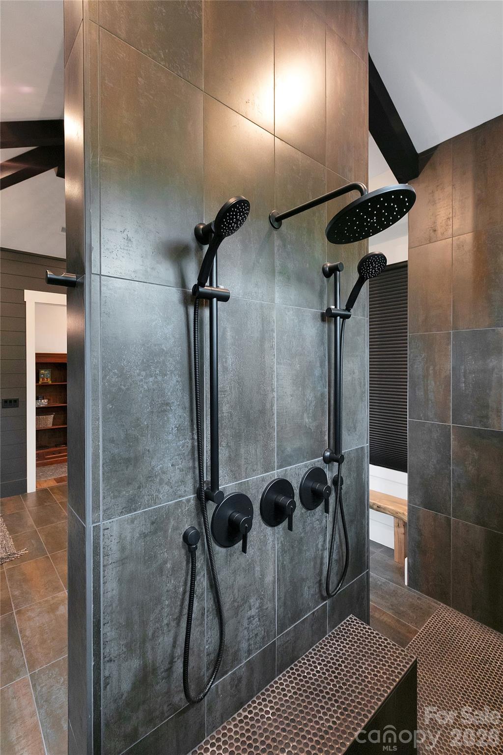 The expansive primary shower offers a spa like experience, featuring dual openings, multiple shower heads and a built in bench for ultimate relaxation. - 726 Ugugu Drive, Brevard