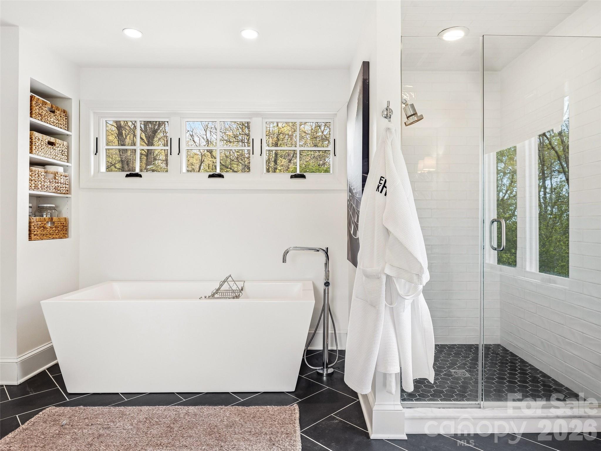 Elegant light filled primary bath with a freestanding soaking tub, frameless glass walk-in shower, and clean, modern finishes throughout. - 10 Kalimar Heights, Hendersonville