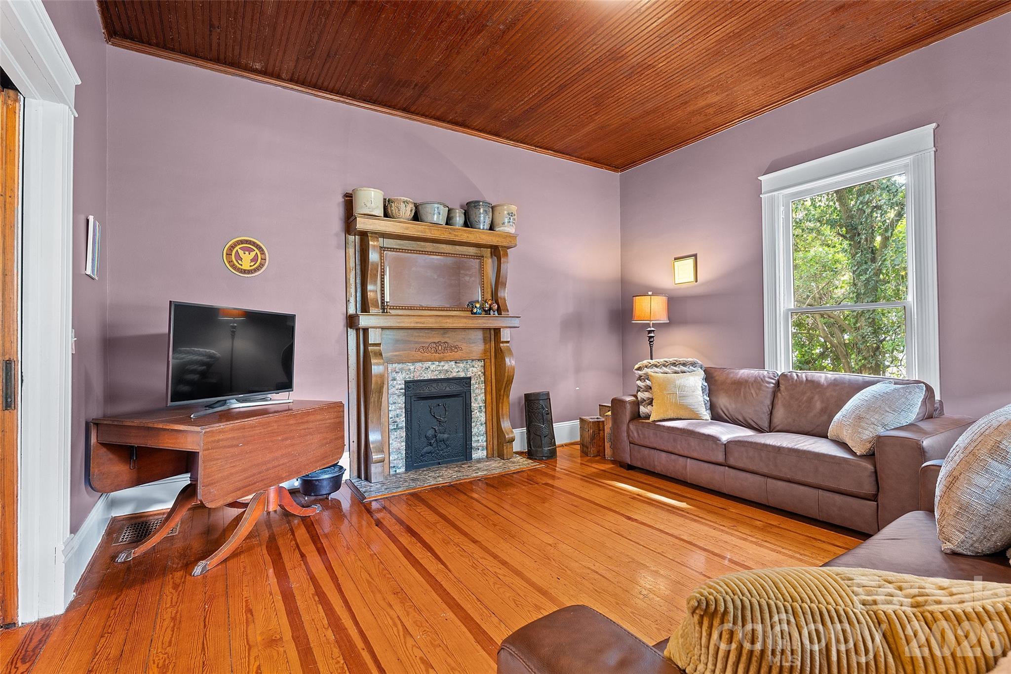 Quaint family room with wood mantel with elegant curved detailing, complemented by a classic tiled surround and decorative cast iron insert—adding timeless character and warmth to the space. - 602 N Main Street, Davidson