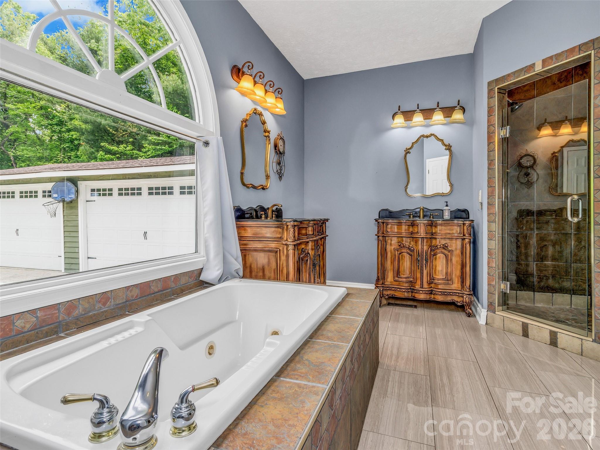 Primary bathroom with jetted tub and his and hers vanities, plus separate tiled shower. - 287 Shady Creek Lane, Hendersonville