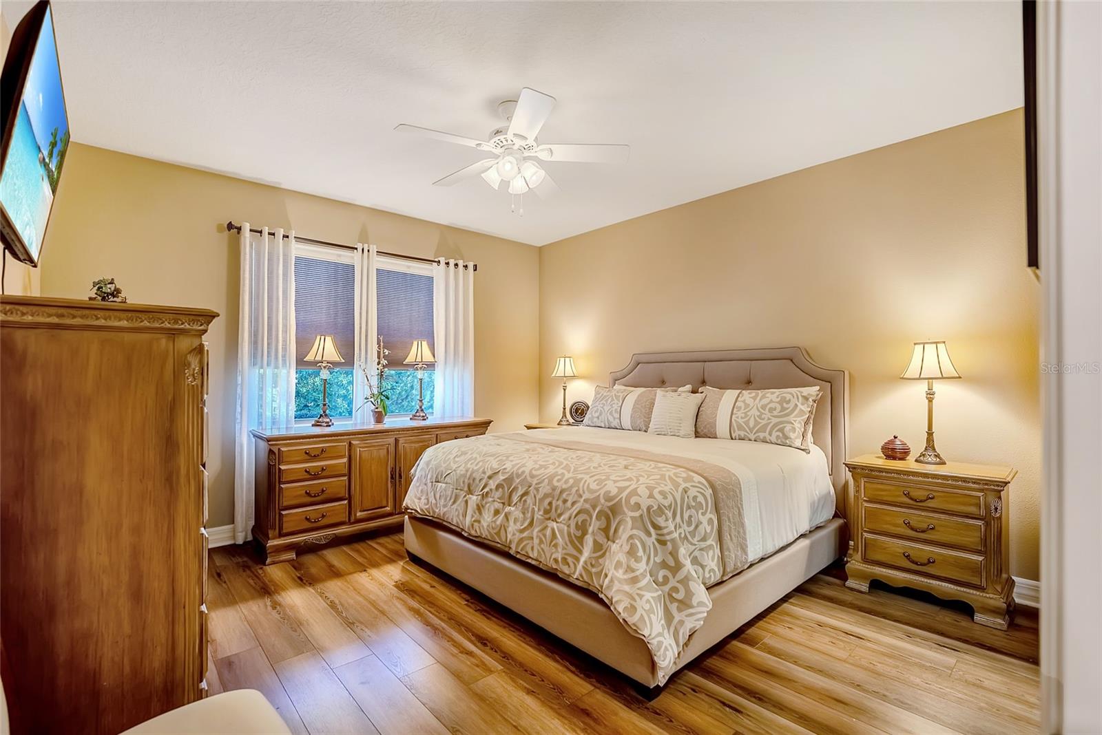 Primary bedroom with ceiling fan and laminate floors - 6707 SW 95TH CIR, OCALA