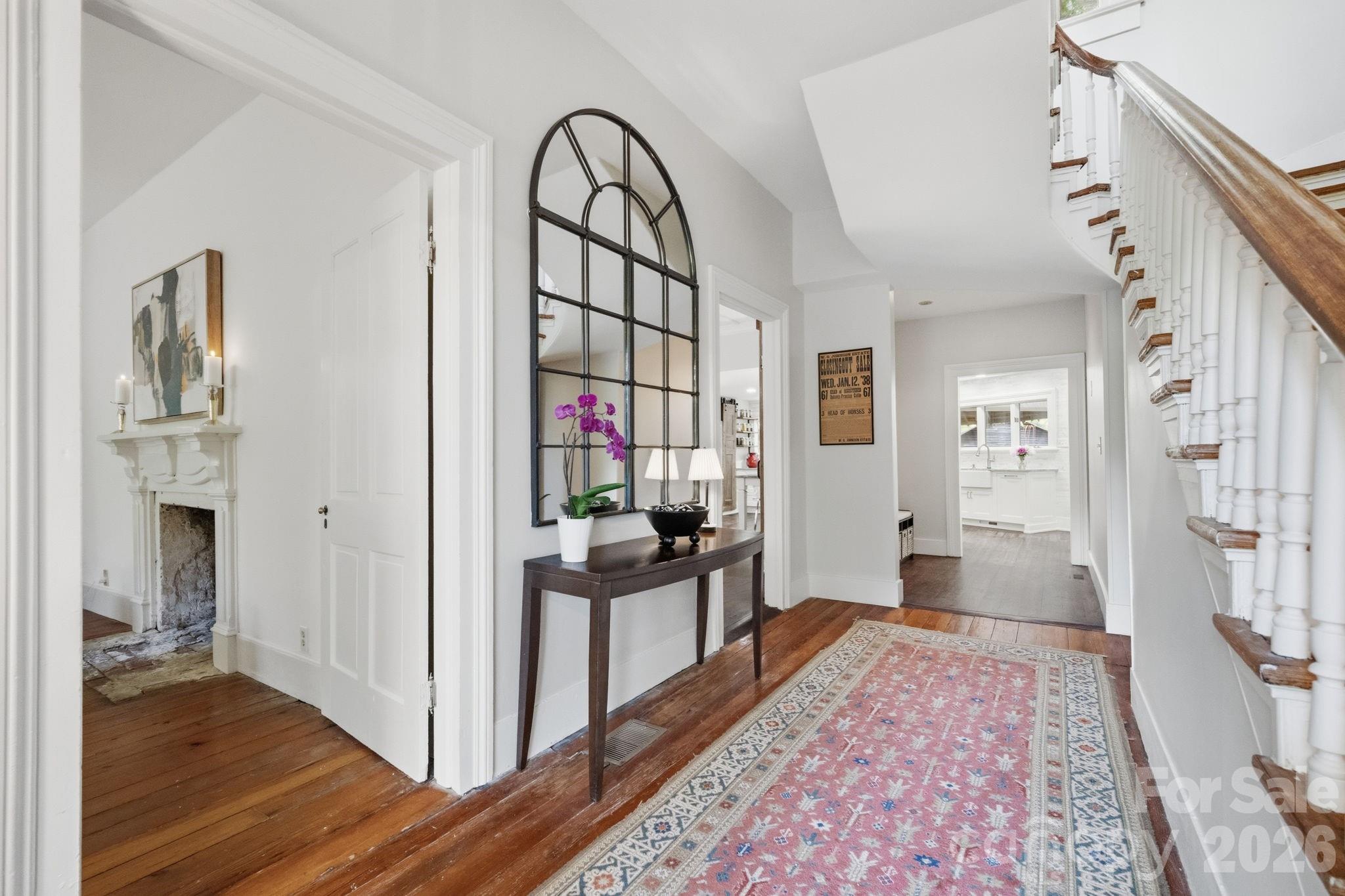 A wide foyer and traditional T-Shaped Vernacular Victorian Farmhouse opens to the original handcrafted staircase with winding switchback design.  Niche area set up as a drop station with coat hooks - 10915 Beatties Ford Road, Huntersville