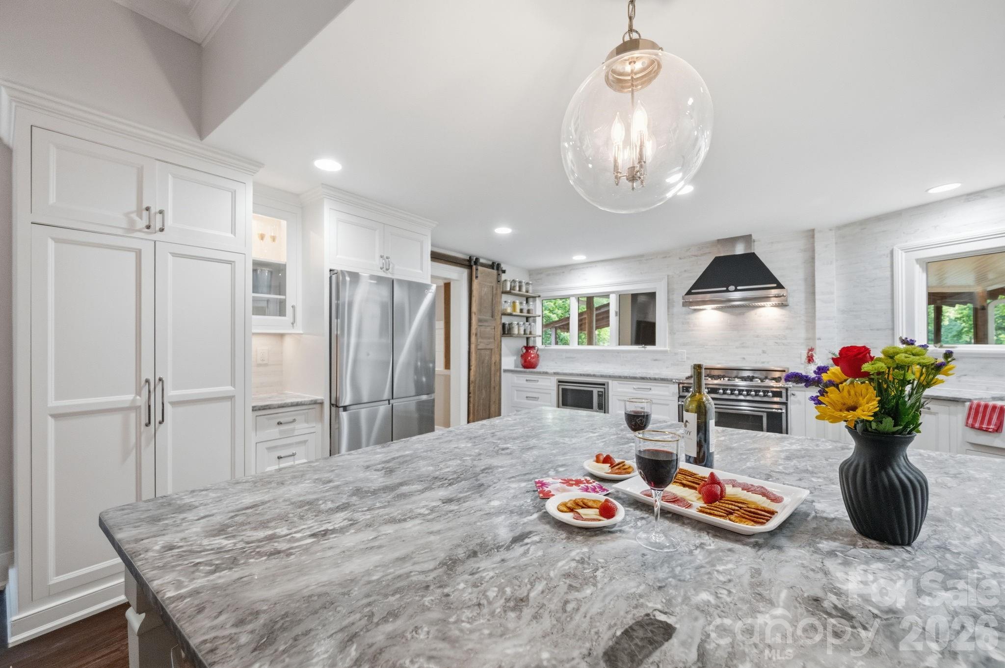 Pantry Wall with pull out shelves, glass display cabinets with under counter lighting, large dining & entertaining island.  Countertop to ceiling tiled accent wall - 10915 Beatties Ford Road, Huntersville