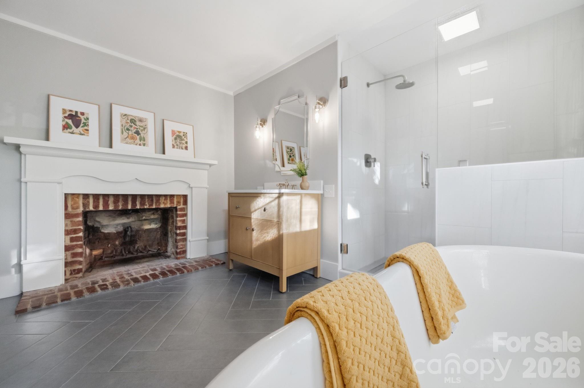 Primary bathroom also renovated, with tile floors, fireplace, soaking tub, tile and frameless glass shower with Hansgrohe raindance shower head and Kohler Malin Studio Vanity. - 10915 Beatties Ford Road, Huntersville