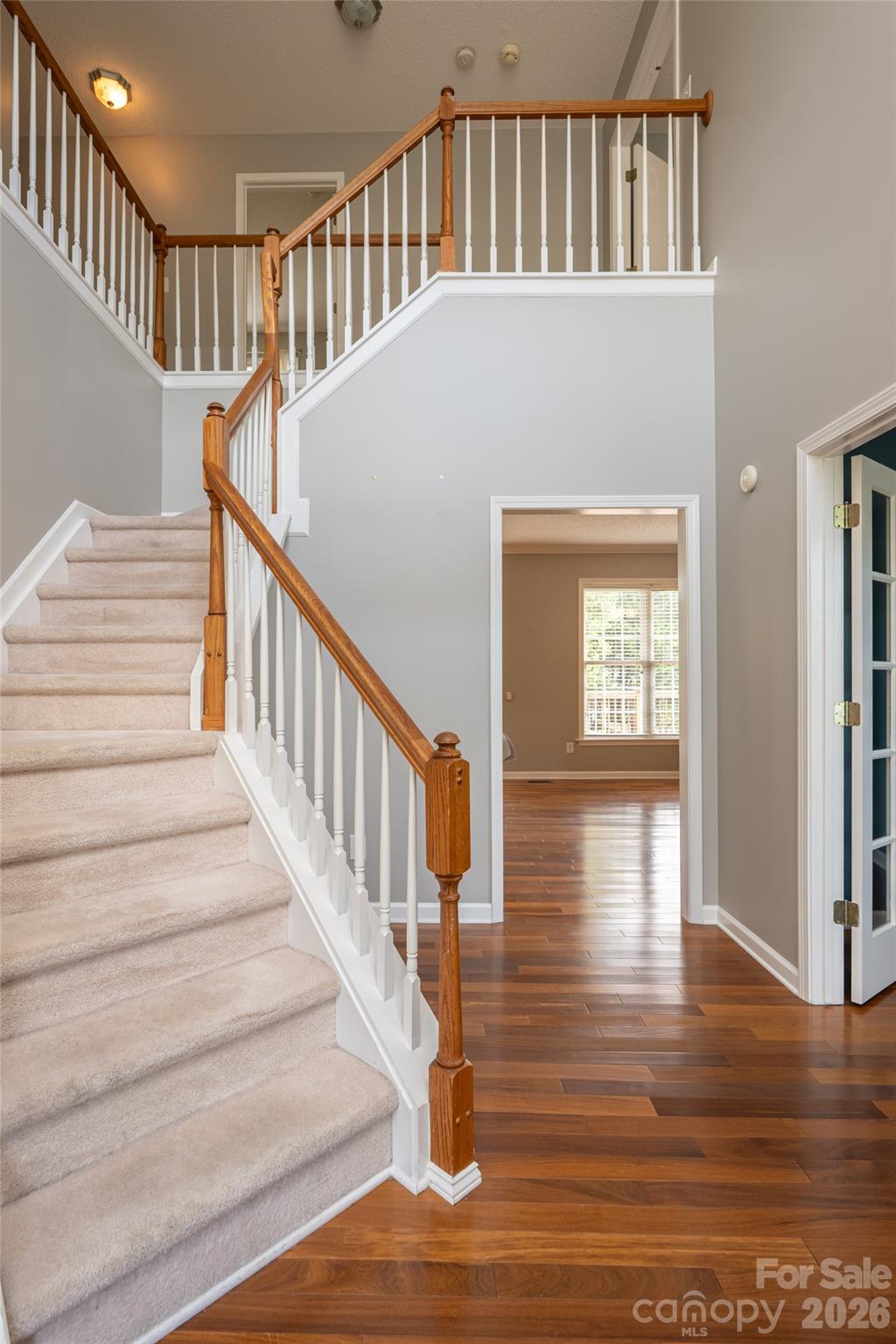 Two-story foyer at the front entry with hardwood floors, staircase to the four upstairs bedrooms, and sightline to the French-door office. - 48 Brownstone Court, Fletcher