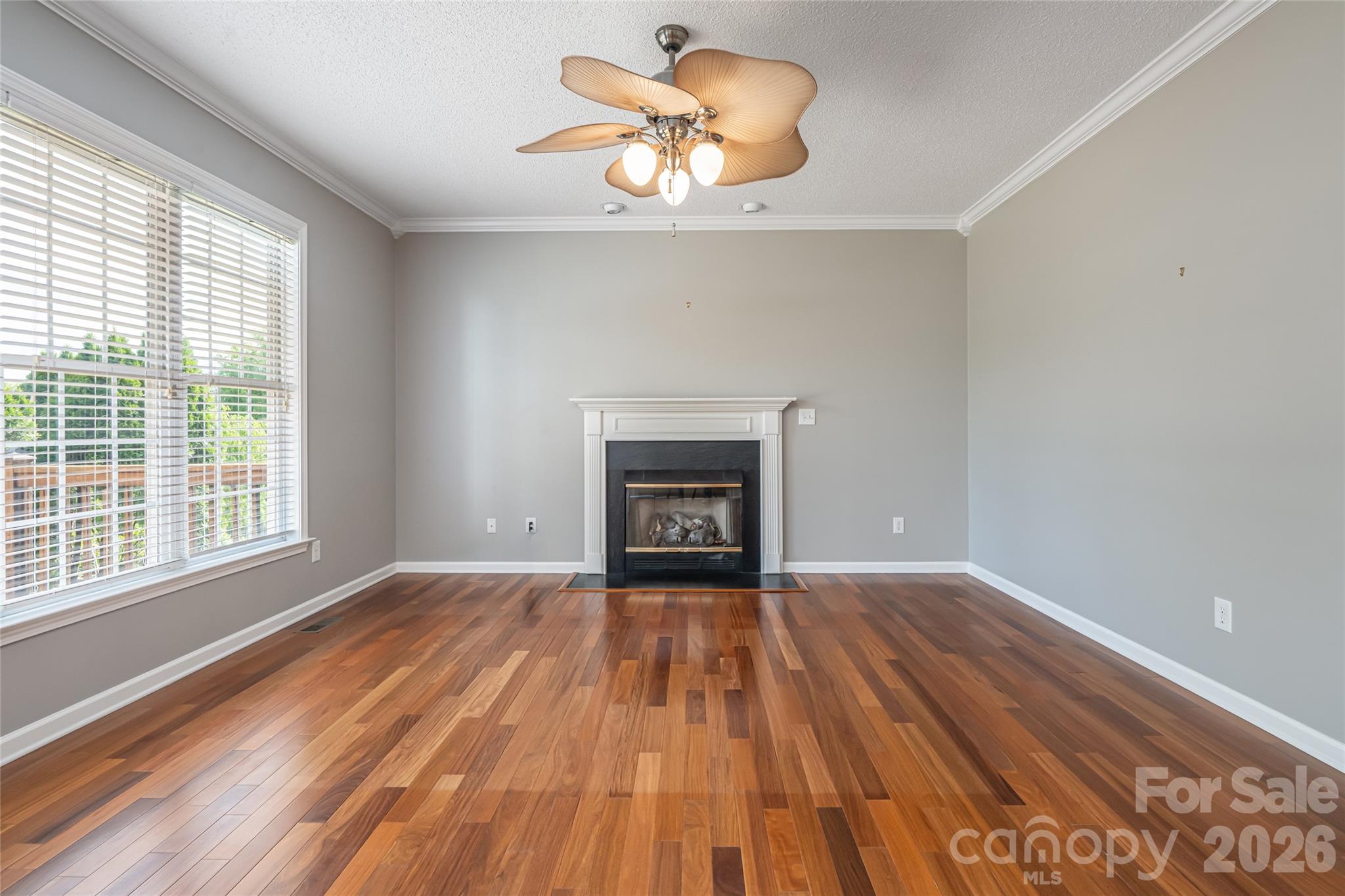 Family room as-is: gas-log fireplace, hardwood floors, ceiling fan, open floor plan to kitchen. - 48 Brownstone Court, Fletcher