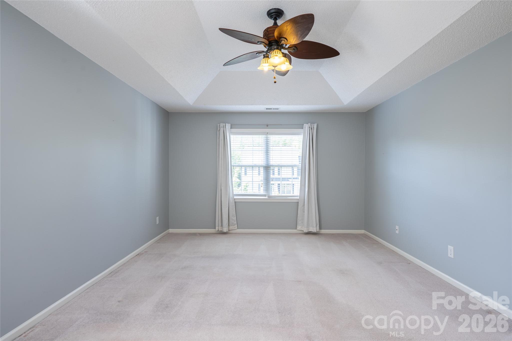 Primary bedroom as-is: tray ceiling, ceiling fan, carpet, natural light. - 48 Brownstone Court, Fletcher