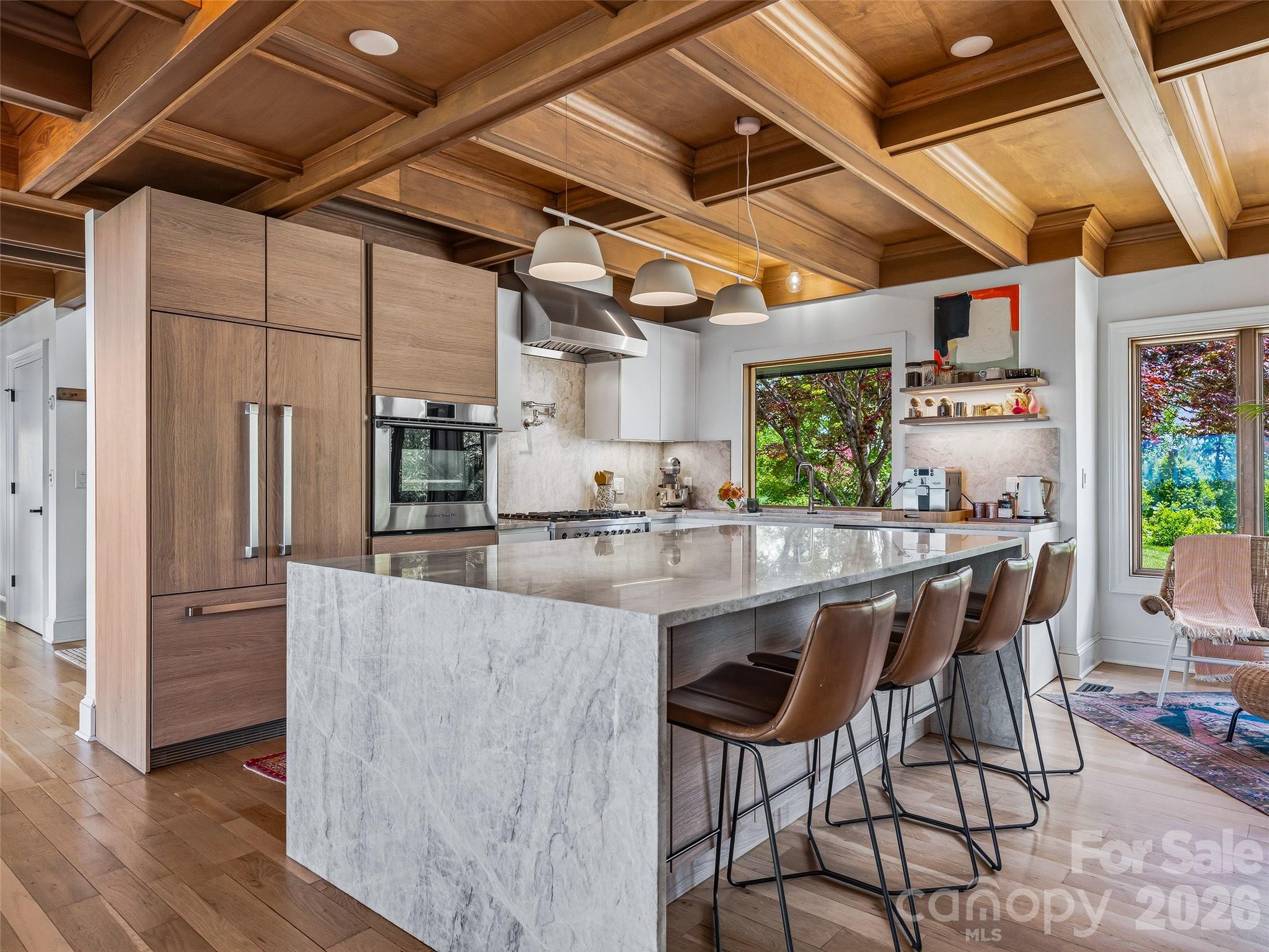 Custom Nobilia Kitchen featuring coffered wood ceiling with crown molding and a Taj Mahal quartzite waterfall island with seating for four. - 100 Big Spring Drive, Asheville