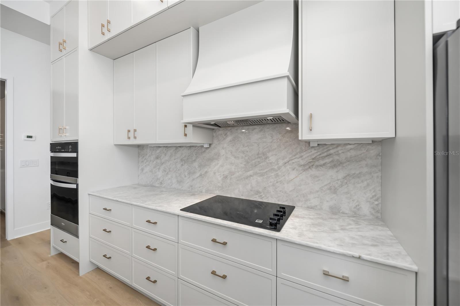 Kitchen Featuring Quartz Backsplash, Custom Range Hood and Double-Stacked Cabinetry. - 16692 LIGGETT CIR, PORT CHARLOTTE